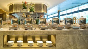 A buffet setup with various food stations, a central decorative plant, and a glass display case. - Winlong International Hotel (Quanzhou)