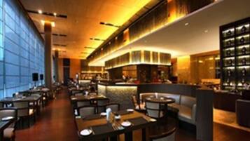 A modern restaurant with a long counter and multiple seating areas.