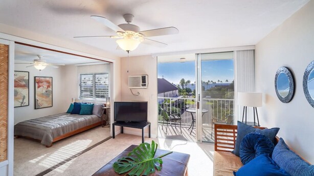 A modern living room with a bed, TV, and a balcony with a view.