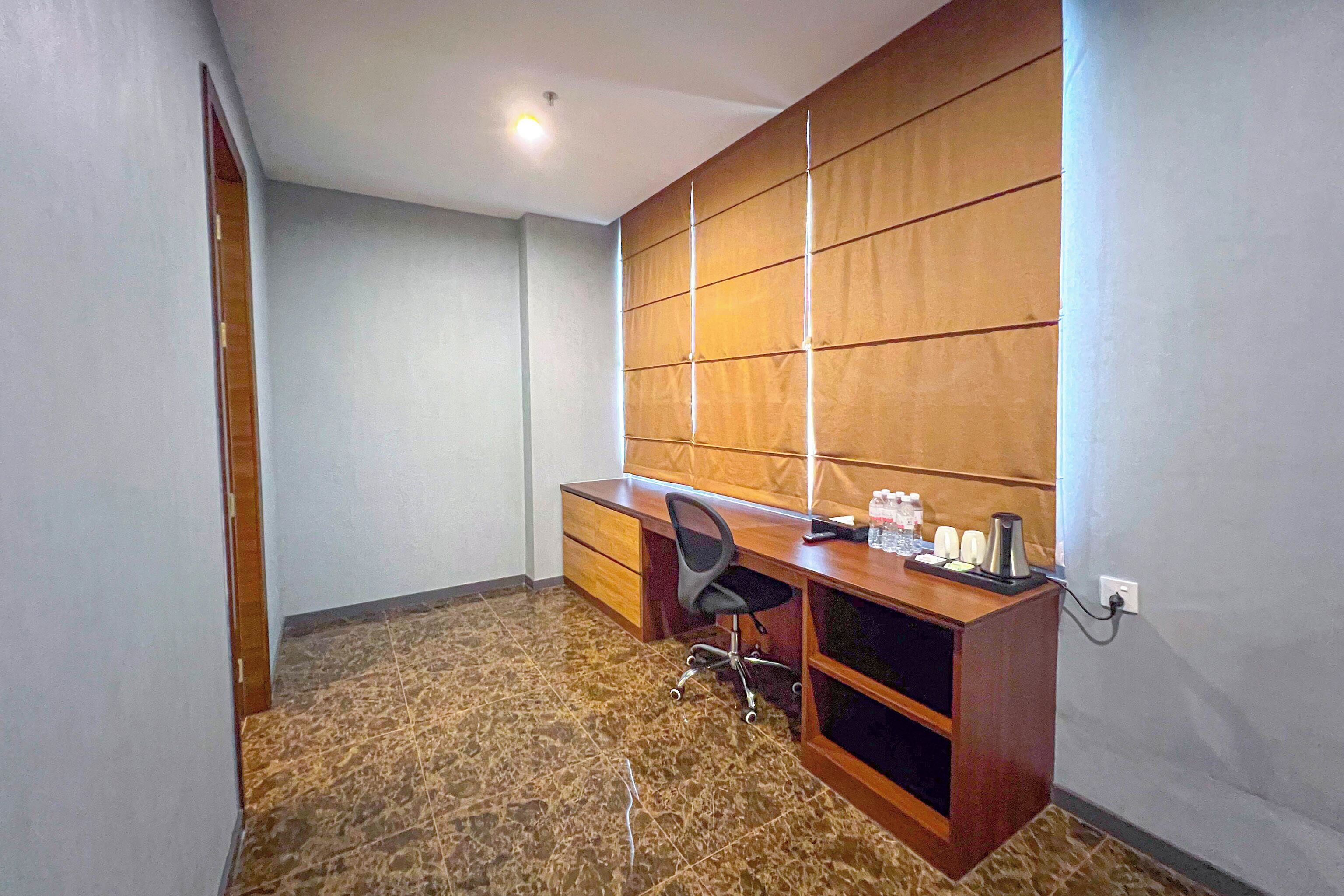A small office with a desk, chair, and a wall-mounted shelf.