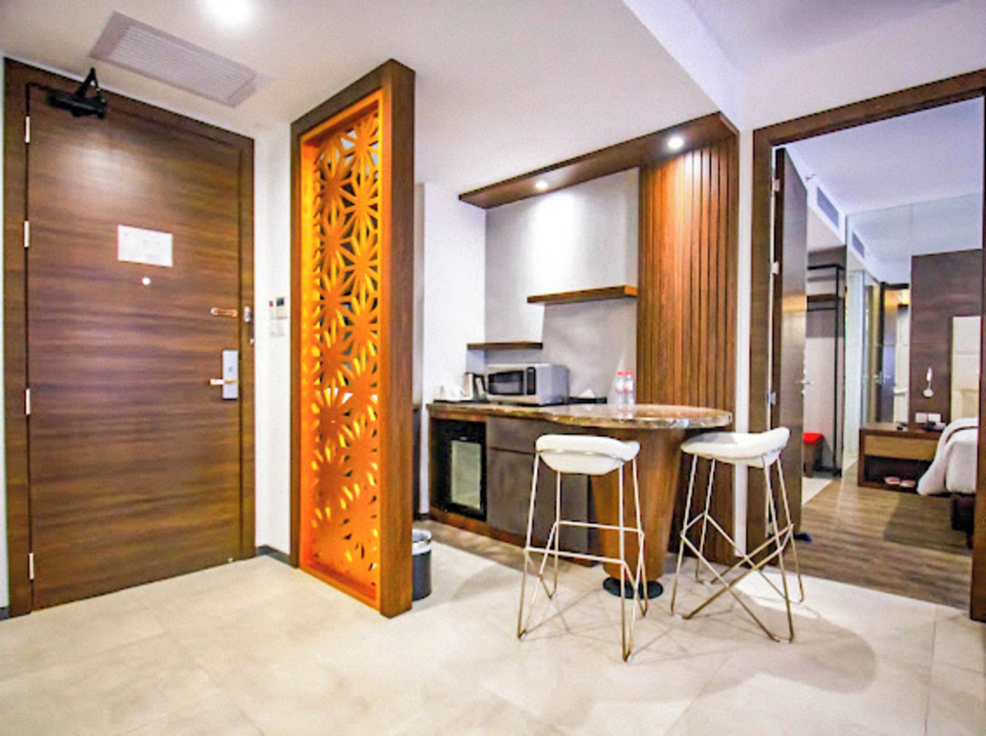A modern kitchen with a wooden door, a decorative panel, and a bar area with stools.