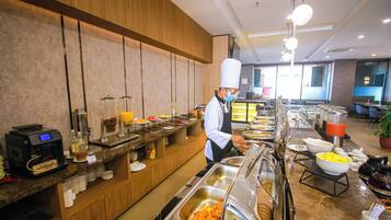 Una mesa de buffet con distintos alimentos y una máquina de café.