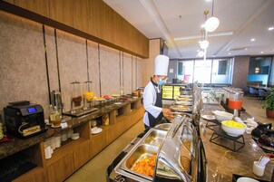 Una mesa de buffet con distintos alimentos y una máquina de café.