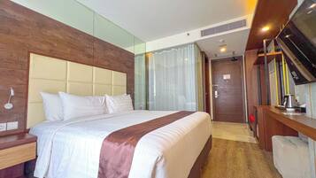 Una habitación de hotel con una cama grande, cabecera de madera, un escritorio con silla y un televisor.