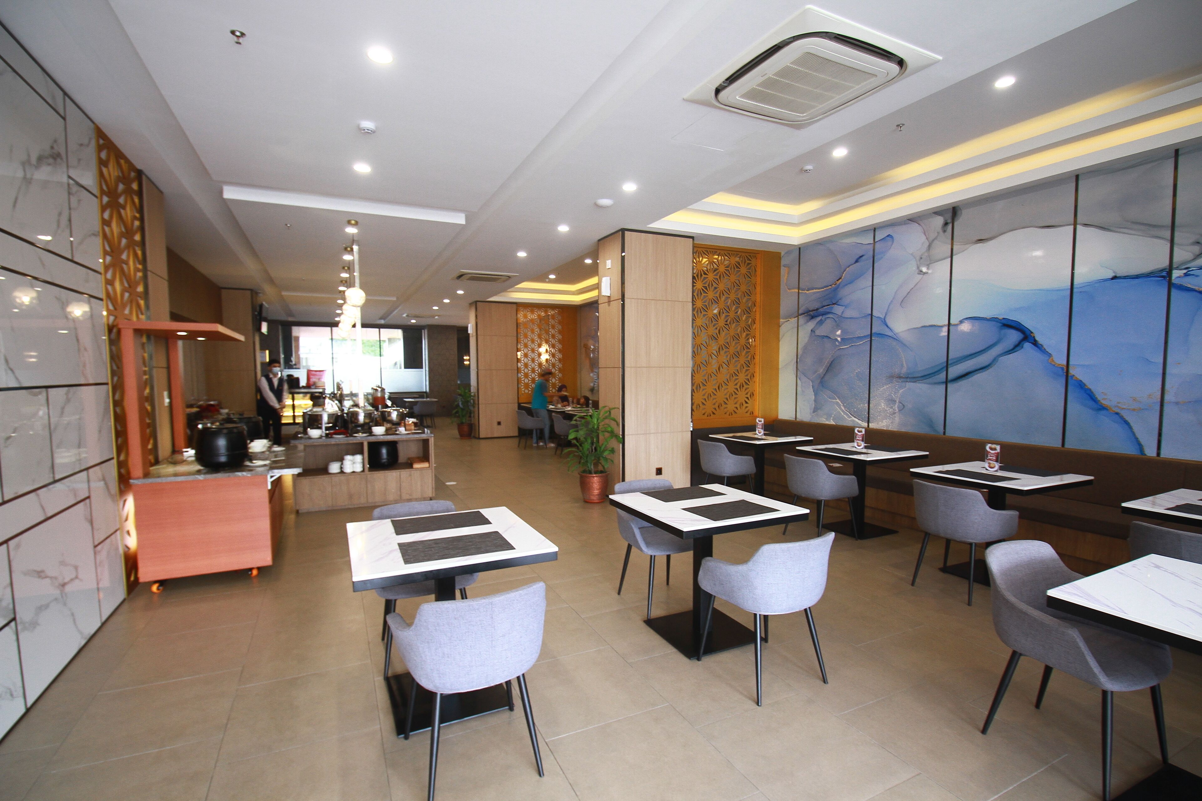 Un restaurante moderno con un interior limpio y minimalista, que ofrece diversas opciones de asientos y un mural decorativo.
