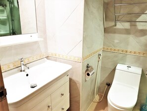 Bathroom features a sink, toilet, and shower area with a glass partition.