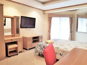 Relax in a serene space with a comfortable bed, desk, and wardrobe, perfect for unwinding.