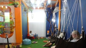 A room with a green carpet, a hammock, bean bags, and a guitar. - Old Quarter View Hanoi Hostel (Hanoi)