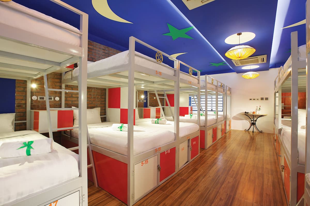 A room with bunk beds, a small table, and a ceiling with star decorations.