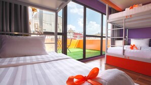A hotel room with two beds, large windows, and a view of a building and greenery outside. - Old Quarter View Hanoi Hostel (Hanoi)