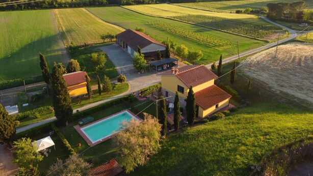 A rural property with a swimming pool, a farmhouse, and surrounding fields.