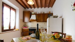 A dining area with a table set for four, a bottle of wine, and a refrigerator in the background.