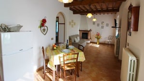 A dining area with a table set for four, a fireplace, and a kitchen area with a refrigerator.