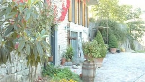 A stone-paved courtyard with a stone building, potted plants, and a garden with yellow flowers. - Villa La Massa - Exclusive Use - Heated Pool (Castel San Niccolo  -  Arezzo)