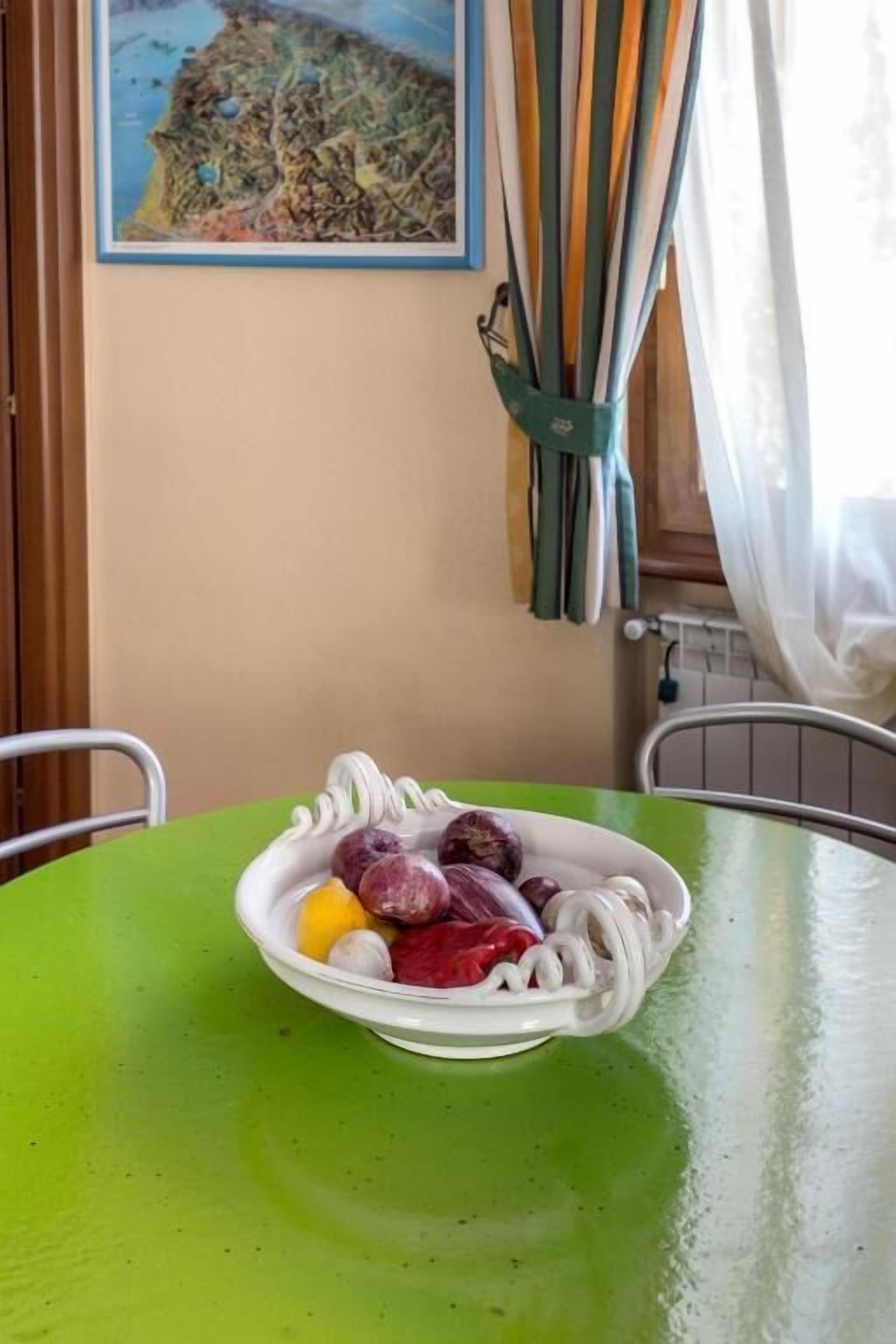 A bowl of noodles with various vegetables on a green table.