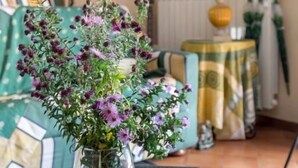 A room with a green suitcase on a table, a vase with purple flowers, a lamp, and a painting on the wall. - Villa La Massa - Exclusive Use - Heated Pool (Castel San Niccolo  -  Arezzo)