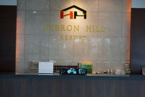 Una reception al Hebron Hill Resort con un logo sopra il nome, un calendario e alcuni oggetti sul banco.