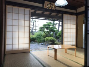 A traditional Japanese room with tatami flooring, a low wooden table, and shoji screens. - Relaxing House de Akemi (Imizu)