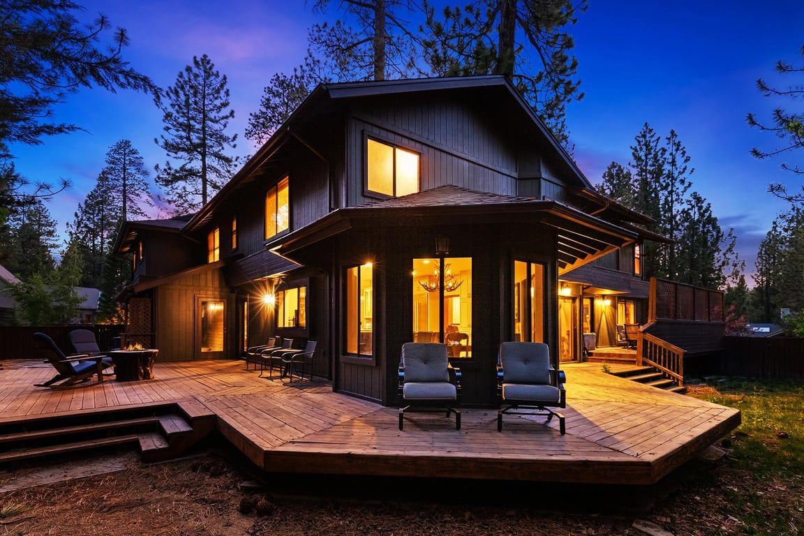 Una casa de madera de dos pisos con un balcón, mobiliario exterior y una escalera que conduce a la entrada.