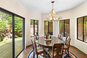 A dining area with a round table, chairs, and a chandelier.