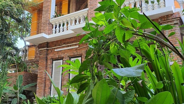 A two-story building with a brick facade and white decorative elements. - Brightness Villa (Battambang)