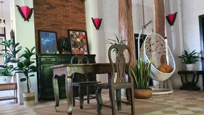A room with a checkered floor, a wooden dining table, chairs, a hanging chair, and potted plants. - Brightness Villa (Battambang)