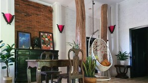 A room with a checkered floor, a wooden chair, a hanging chair, and a brick wall. - Brightness Villa (Battambang)