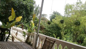 A balcony with a table and chairs, surrounded by lush greenery and a view of dense foliage. - Brightness Villa (Battambang)