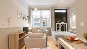 Une chambre d'hôtel compacte comprenant un canapé, une petite table avec un plateau de petit-déjeuner, une télévision et une fenêtre donnant sur la rue.