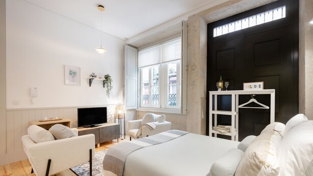 Une chambre moderne avec un lit, un canapé, une télévision et une armoire.