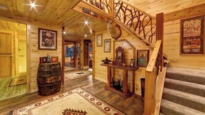 A wooden interior with a staircase, a wooden barrel, and a rug.