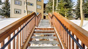 A wooden staircase with metal steps leading up to a building with multiple windows. - Chic & Cozy Breck Condo: Ski-In/Ski-Out at Peak 8! (Breckenridge)