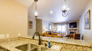 A kitchen with a granite countertop, stainless steel sink, and a hanging light fixture. - Chic & Cozy Breck Condo: Ski-In/Ski-Out at Peak 8! (Breckenridge)