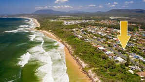 An aerial view of a coastal town with a beachfront, residential areas, and a large yellow arrow pointing to a specific location. - Salt Breeze - upstairs only (Lake Cathie)
