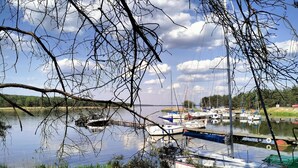 A calm lake with boats docked, surrounded by greenery and trees.