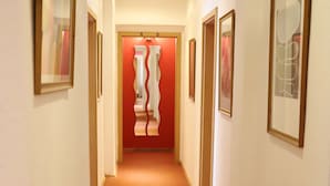 A hallway with framed pictures on the walls, a carpeted floor, and a door at the end. - Hotel Romina (Frankfurt)