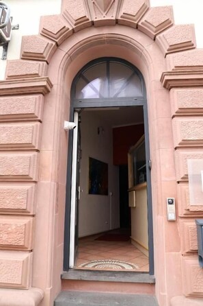 An arched entrance with a door, a small rug, and a wall-mounted intercom. - Hotel Romina (Frankfurt)