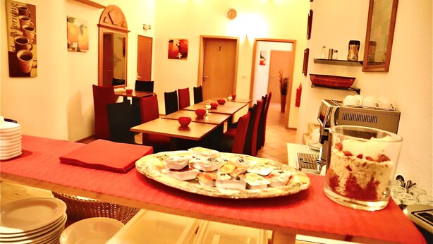 A dining area with a pizza on a table, a glass of dessert, and various dishes and utensils. - Hotel Romina (Frankfurt)
