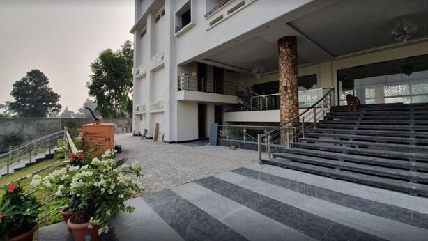 Un edificio moderno con una escalera que lleva a un piso superior, un pilar de piedra y plantas en macetas al frente.