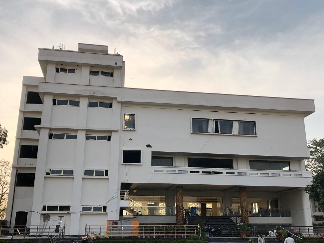 A modern multi-story building with a flat roof, large windows, and a central open area with steps leading up to it.