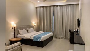 Habitación de hotel con cama, mesitas de noche, escritorio, silla, televisión y ventilador de techo.