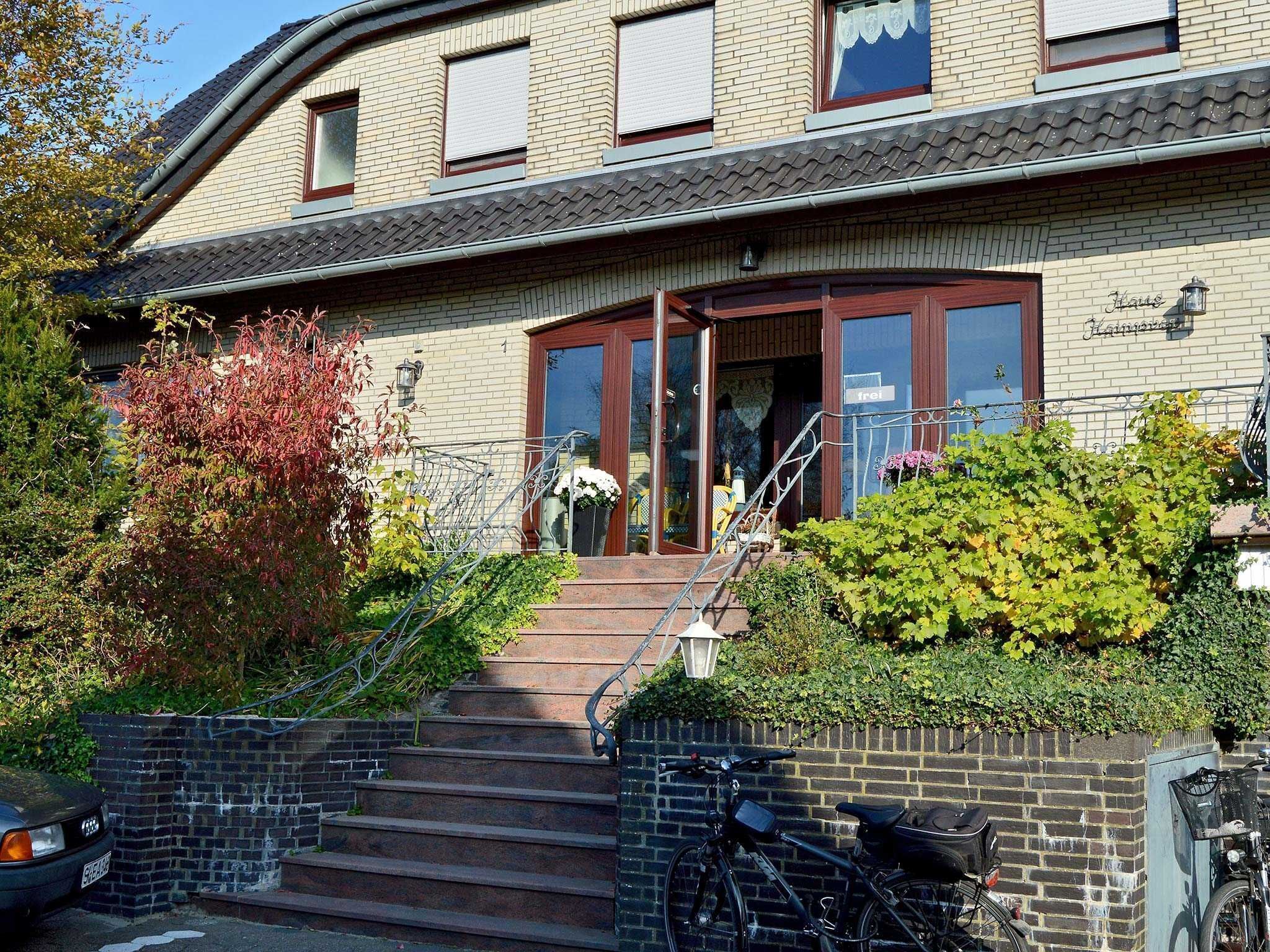 A two-story building with a brick facade, a wooden door, and a staircase leading to the entrance.