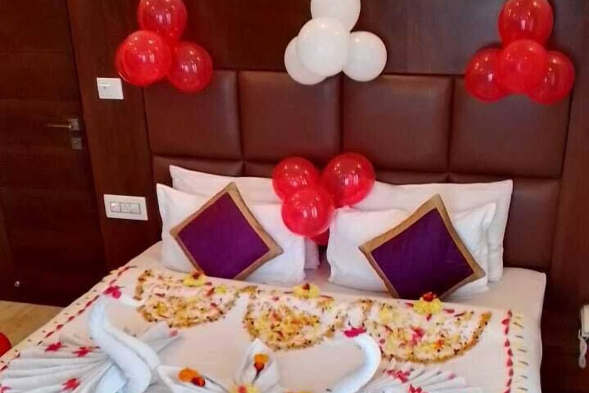 A bed with a white bedspread, red and white balloons, and decorative swans made from towels.