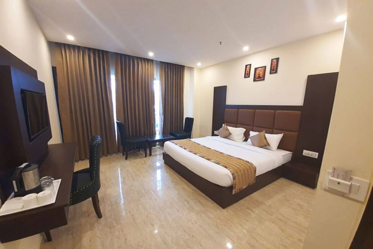 A hotel room with a bed, a desk with a chair, a television, and a coffee maker.