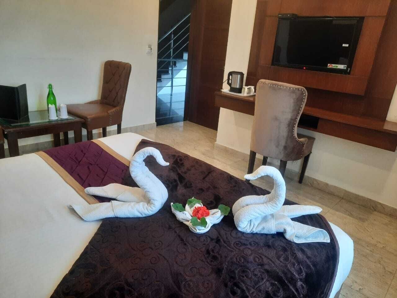 Habitació d'hotel amb un llit, dues cadires, un televisor i una cafetera.