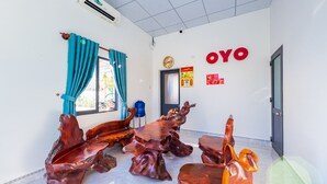 Una habitación con un ventanal grande, cortinas color turquesa, dispensador de agua y una pared con la palabra "OYO".