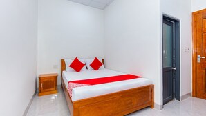 Un dormitorio con cama de madera, paredes blancas y colcha roja.