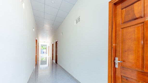 Un pasillo con puertas de madera, paredes blancas y suelo de baldosas.
