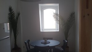 A dining area with a round table, chairs, a pendant light, and two potted plants. - Apartment 100 m² in a mansion (Munster)