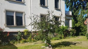 A residential building with a well-maintained lawn and a small tree in the front yard. - Apartment 100 m² in a mansion (Munster)
